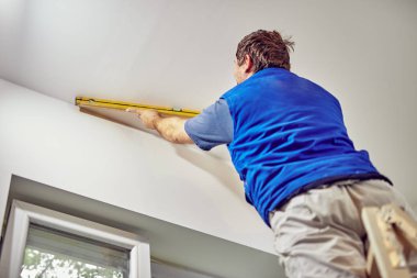 İşçi evin içindeki duvarlar için balon seviyesini kullanıyor - renovatio