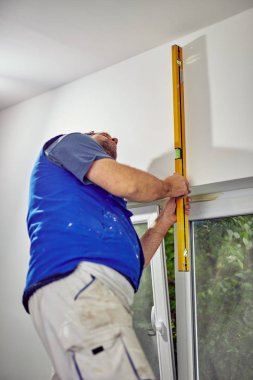 İşçi evin içindeki duvarlar için balon seviyesini kullanıyor - renovatio