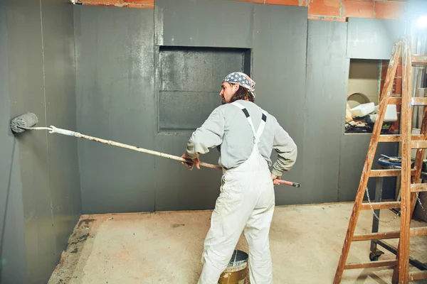 Pintor pintando paredes con un rodillo extensor en interiores . — Foto de Stock