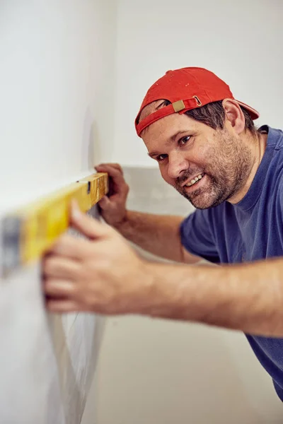 Trabajador utilizando el nivel de burbuja para las paredes y azulejos dentro de la casa  - — Foto de Stock