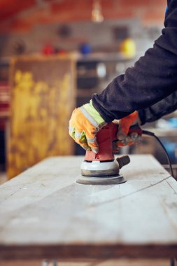 Marangoz antika bir eserde yörünge elektrikli zımpara makinesi kullanıyor.