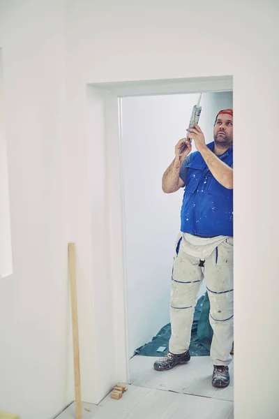 Trabajador que usa silicona para paredes y marco de puerta dentro de la casa — Foto de Stock