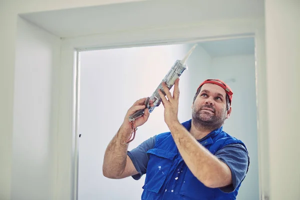 Trabajador que usa silicona para paredes y marco de puerta dentro de la casa — Foto de Stock