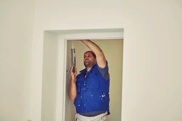 Lavoratore che utilizza silicone per pareti e telaio della porta all'interno della casa — Foto Stock