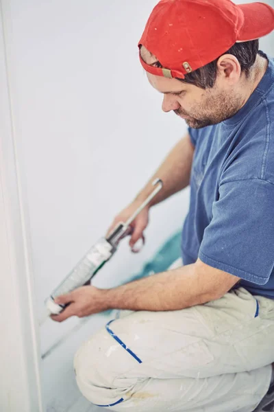 Работник, использующий силикон для стен и дверной рамы внутри дома — стоковое фото