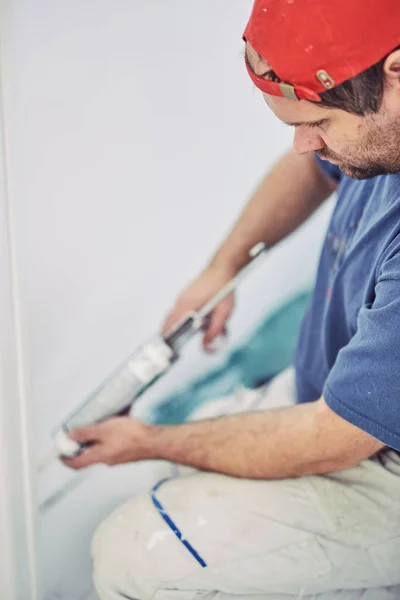 Работник, использующий силикон для стен и дверной рамы внутри дома — стоковое фото