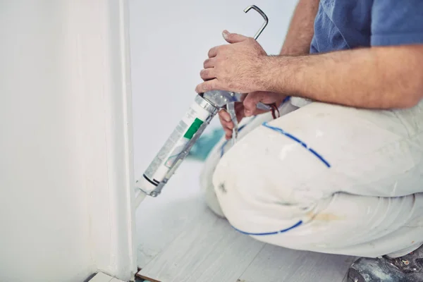 Trabalhador usando silicone para paredes e moldura da porta dentro da casa — Fotografia de Stock