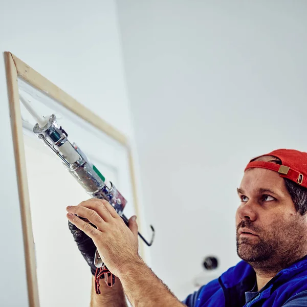 Εργαζόμενος που χρησιμοποιεί σιλικόνη για τοίχους και πλαίσιο πόρτας μέσα στο σπίτι — Φωτογραφία Αρχείου
