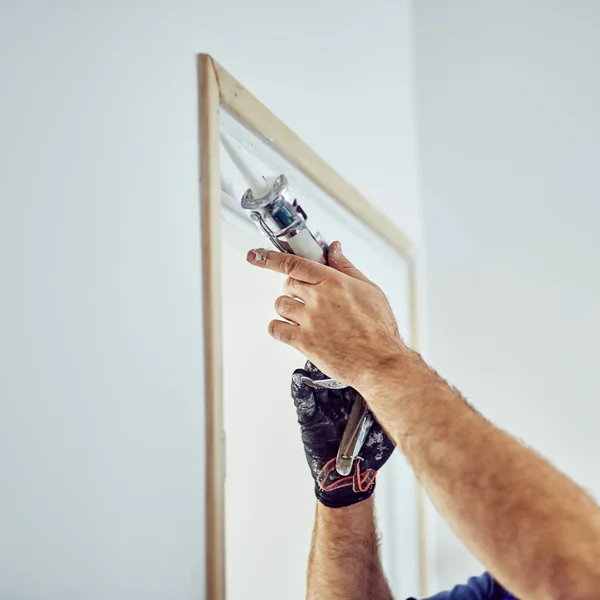 Trabajador que usa silicona para paredes y marco de puerta dentro de la casa — Foto de Stock