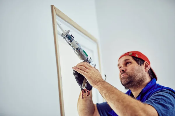 Pracovník používající silikon pro zdi a rám dveří uvnitř domu — Stock fotografie