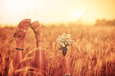 Kız çiçek tutan ve bir buğday alanında yalan.