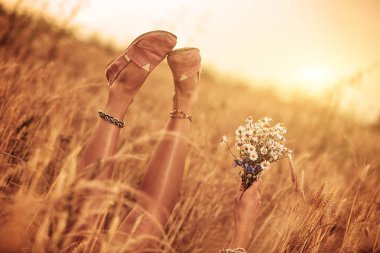 Kız çiçek tutan ve bir buğday alanında yalan.