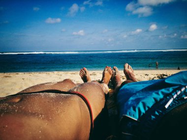 Çiftler kumlu bir plajda uzanıp eğleniyorlar..