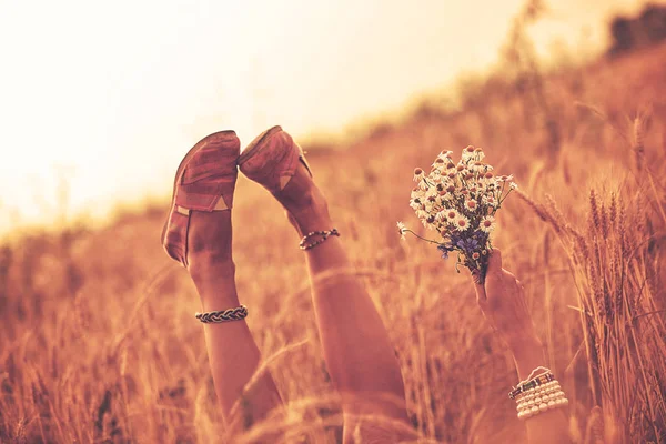 Девушка с цветами и лежа на пшеничном поле . — стоковое фото