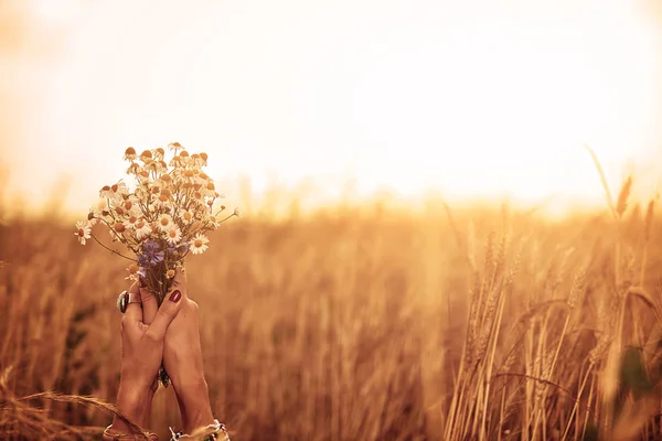 Ragazza che tiene fiori e giace in un campo di grano . — Foto Stock