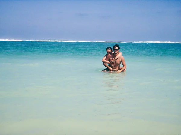Ζευγάρι απολαμβάνει σε μια τροπική παραλία αμμώδης ωκεανό. — Φωτογραφία Αρχείου