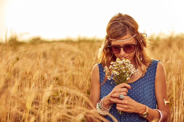 Γυναίκα με μπουκέτο λουλουδιών σε ένα χωράφι σιταριού. — Φωτογραφία Αρχείου
