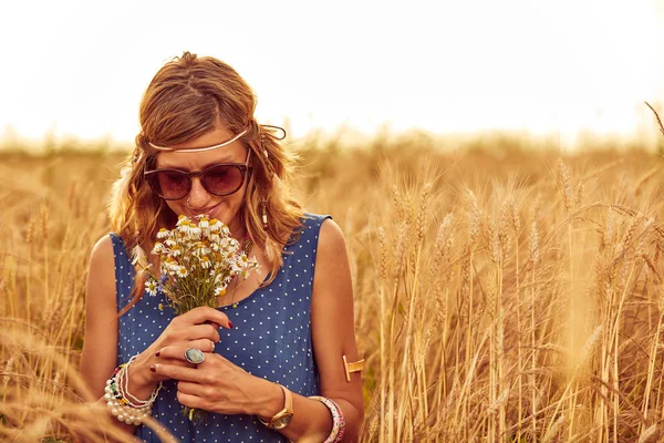 Woman with bouquet of flowers in a wheat field. — Stock Photo, Image