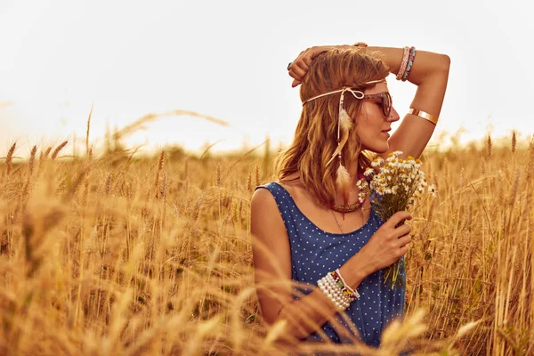 Woman with bouquet of flowers in a wheat field. — Stock Photo, Image