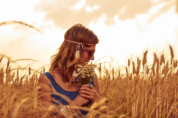 Woman with bouquet of flowers in a wheat field. — Stock Photo, Image