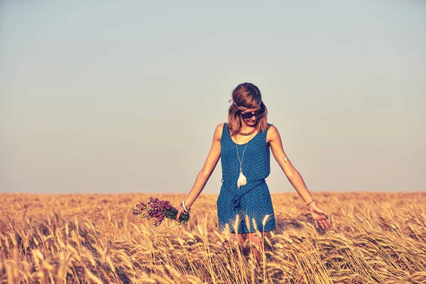Жінка з букетом квітів на пшеничному полі . — стокове фото