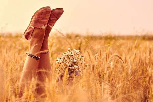Дівчина тримає квіти і лежить на пшеничному полі . — стокове фото