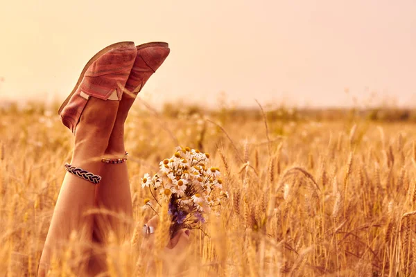 Дівчина тримає квіти і лежить на пшеничному полі . — стокове фото