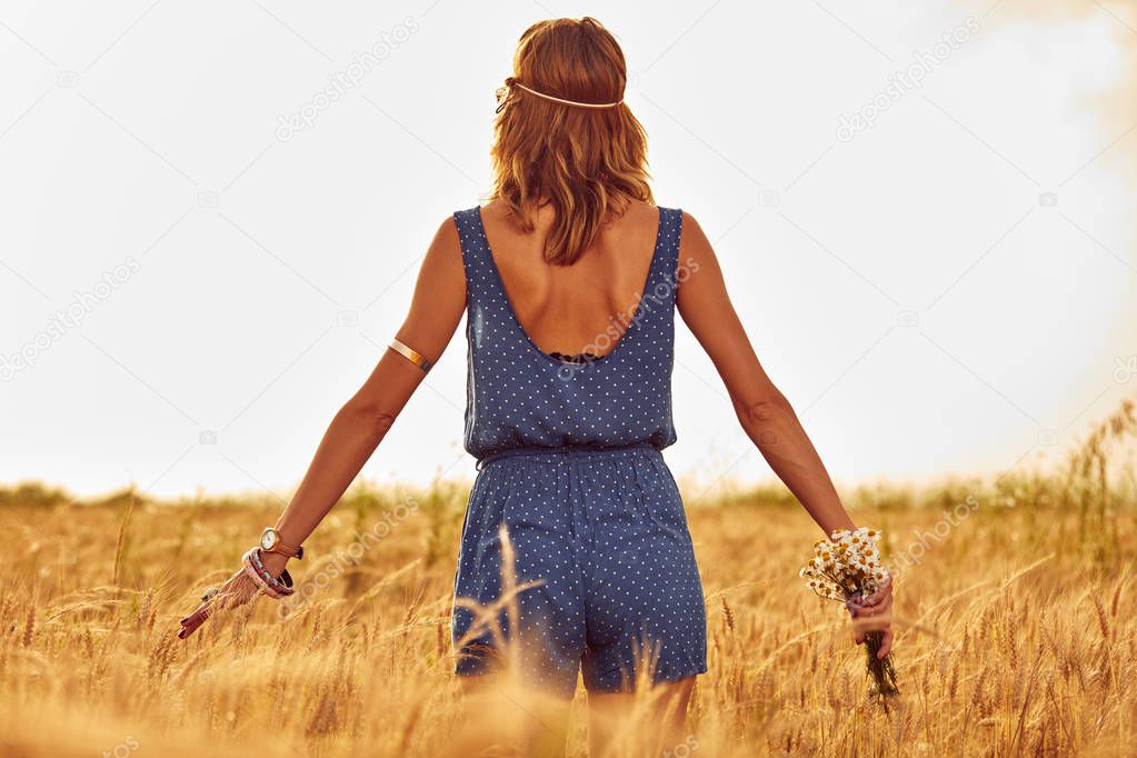 Woman with bouquet of flowers in a wheat field.