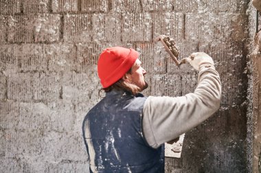 Gerçek inşaat işçisi yeni evin içinde bir duvar yapma.