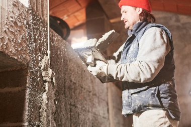 Gerçek inşaat işçisi yeni evin içinde bir duvar yapma.