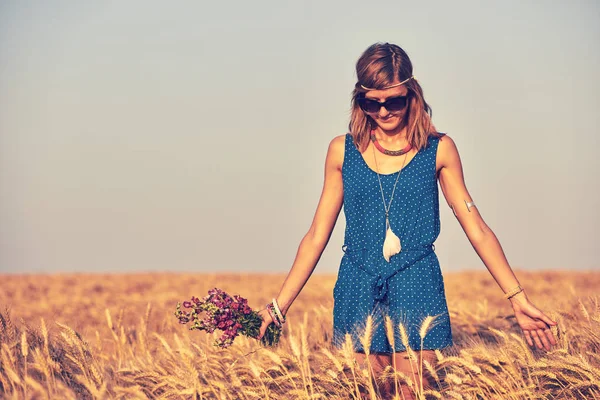 Woman with bouquet of flowers in a wheat field. — Stock Photo, Image