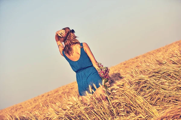 Mujer con ramo de flores en un campo de trigo . — Foto de Stock