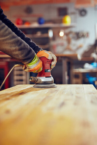 Мужчина плотник, использующий орбитальный электрошлифовальный станок в ретро-винтаже
 