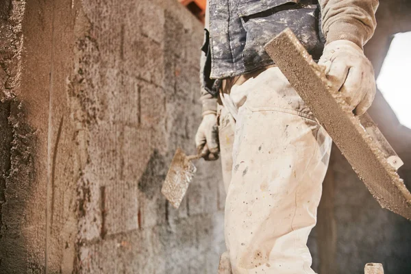 Opravdový stavební pracovník, který dělá v novém domě zeď. — Stock fotografie