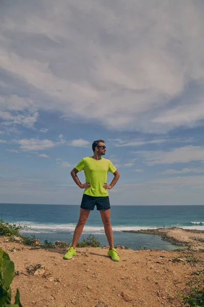 Deportista estirándose en un acantilado tropical exótico cerca del océano . — Foto de Stock