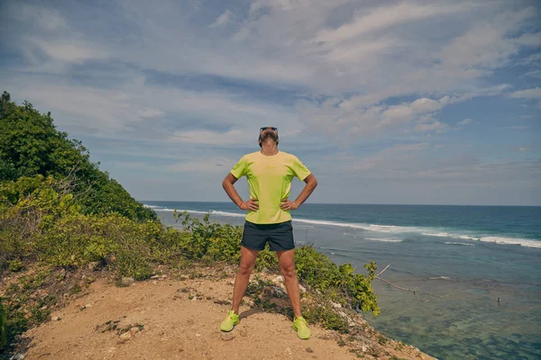 Deportista estirándose en un acantilado tropical exótico cerca del océano . —  Fotos de Stock