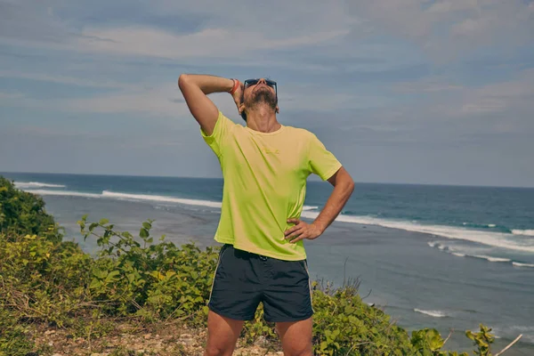 Sportivo che si estende su una scogliera esotica tropicale vicino all'oceano . — Foto Stock