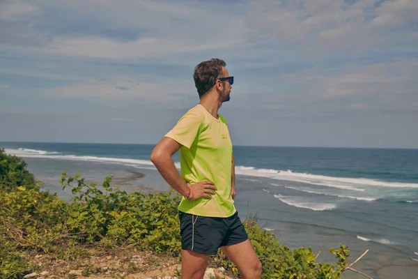 Sportivo che si estende su una scogliera esotica tropicale vicino all'oceano . — Foto Stock
