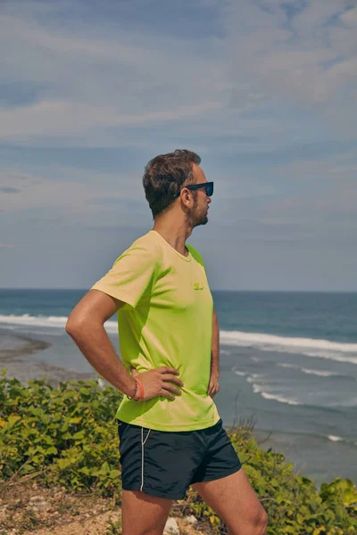 Deportista estirándose en un acantilado tropical exótico cerca del océano . —  Fotos de Stock