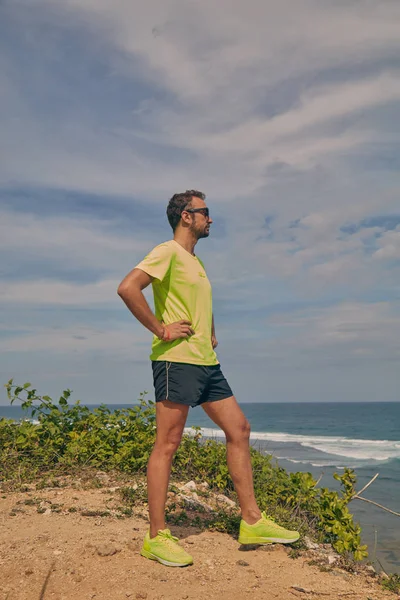 Deportista estirándose en un acantilado tropical exótico cerca del océano . — Foto de Stock