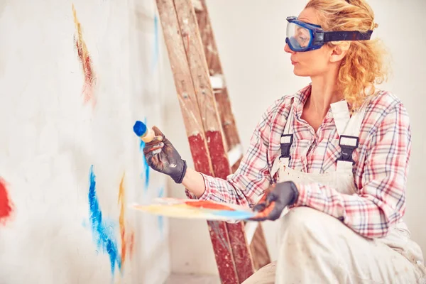 Working woman plastering / painting walls inside the house.