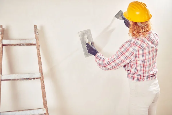 Arbeitende Frau verputzt / streicht Wände im Haus. — Stockfoto