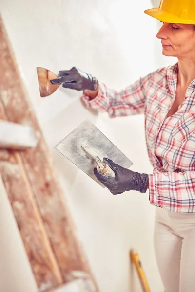 Рабочая женщина штукатурка / покраска стен внутри дома . — стоковое фото