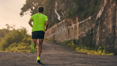 Banliyö dağ yolunda yokuş aşağı/yokuş yukarı adam jogging.