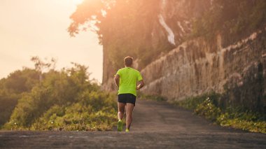 Banliyö dağ yolunda yokuş aşağı/yokuş yukarı adam jogging.