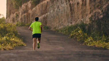 Banliyö dağ yolunda yokuş aşağı/yokuş yukarı adam jogging.
