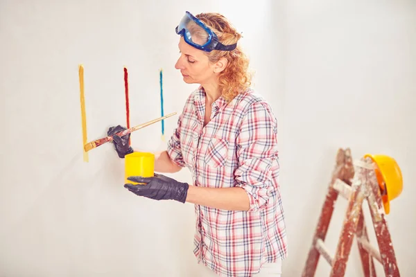 Mujer trabajadora enyesando / pintando paredes dentro de la casa . — Foto de Stock