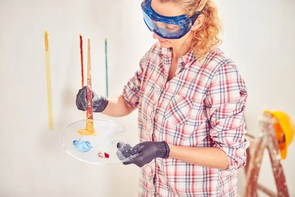 Робоча жінка штукатурка / фарбування стін всередині будинку . — стокове фото