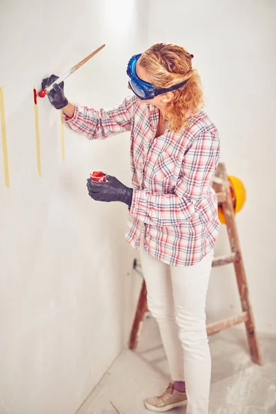 Mujer trabajadora enyesando / pintando paredes dentro de la casa . — Foto de Stock