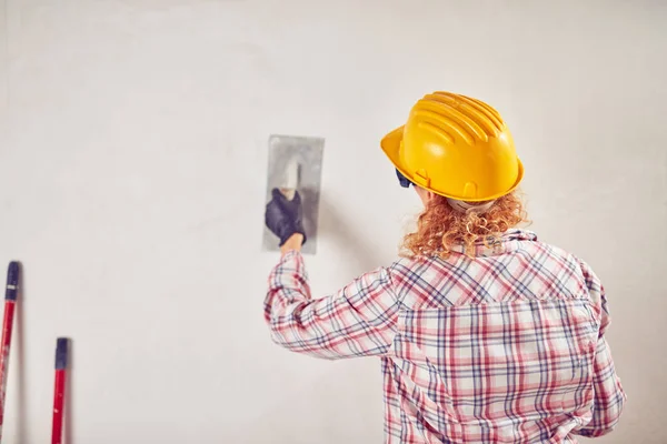 Mujer trabajadora enyesando / pintando paredes dentro de la casa . — Foto de Stock